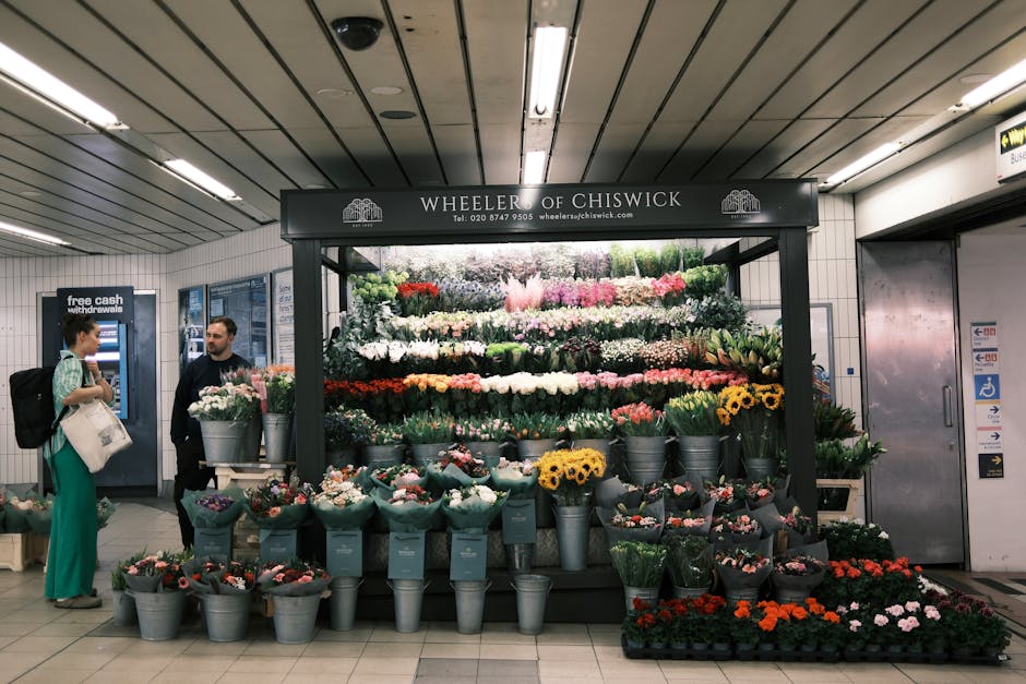 A floral display at Wheler of Chiswick situated in an underground station, featuring an extensive arrangement of fresh flowers including roses, tulips, sunflowers, daisies, and orchids in various colo
